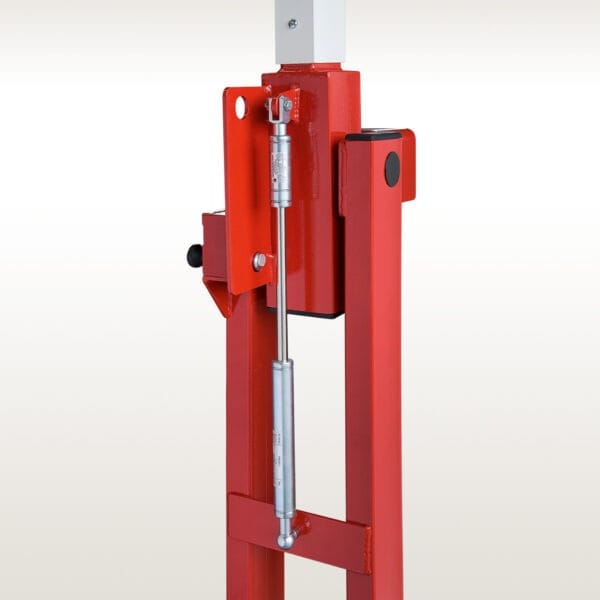 Detailaufnahme einer COMPACT Systemschranke mit rotem Metallrahmen und silbernem Pneumatikzylinder vor neutralem Hintergrund.