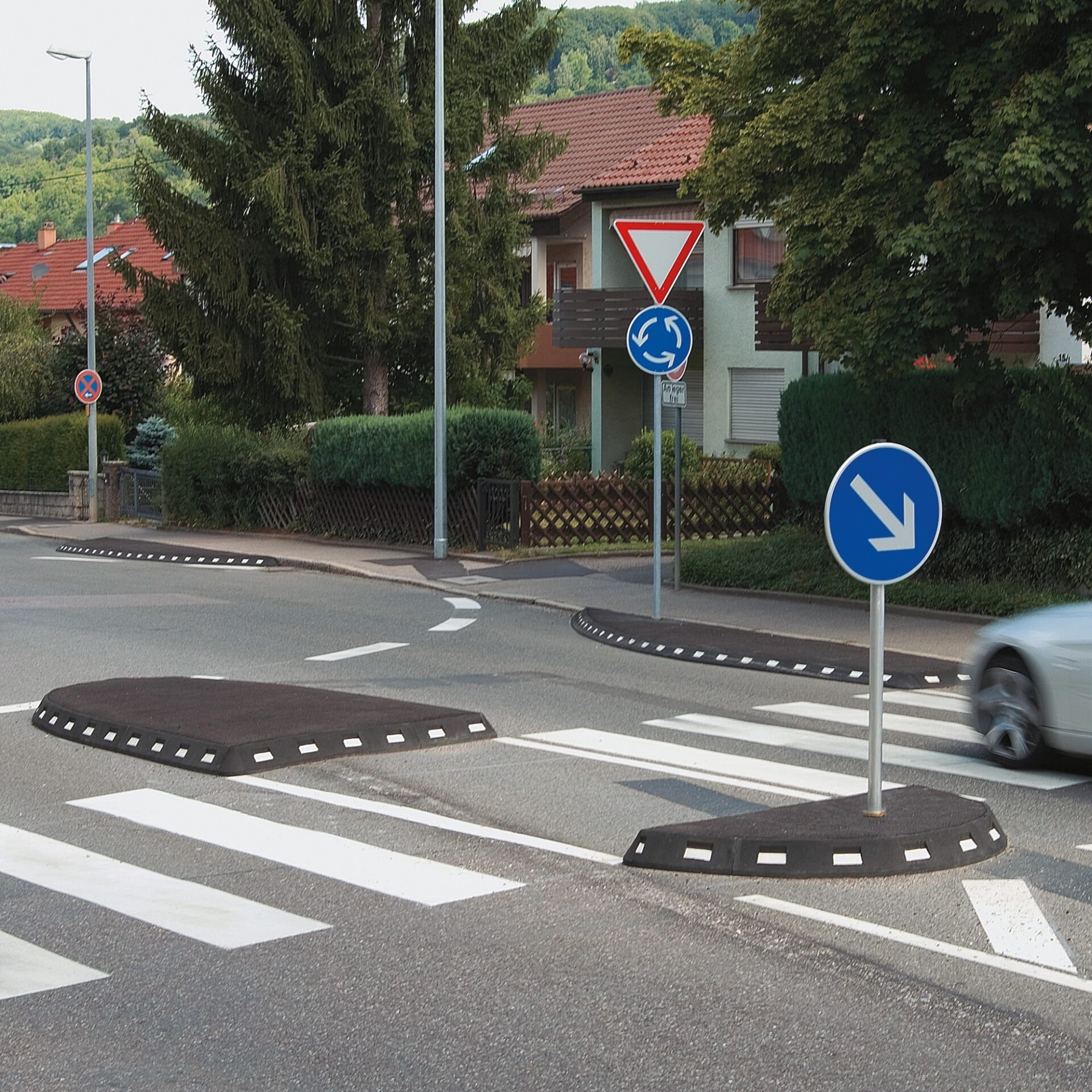 Auto nähert sich einem Kreisverkehr mit GAMMA Elastikbordstein, Zebrastreifen und gut sichtbaren Verkehrsschildern im Wohngebiet.