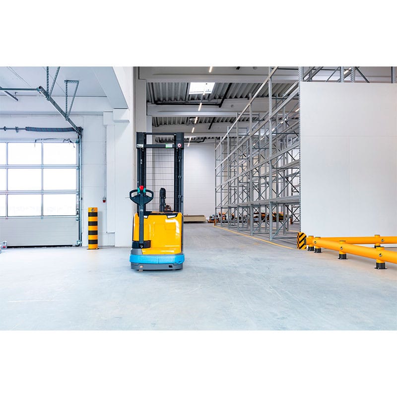 Rack-Mammut Rammschutzbarriere am Boden eines großen, modernen Lagers mit leeren Metallregalen installiert.