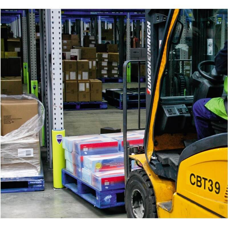 Ein Arbeiter fährt einen gelben Gabelstapler und bewegt eine blaue Palette mit Kartons in Lagerhalle mit Regalstützenschutz.