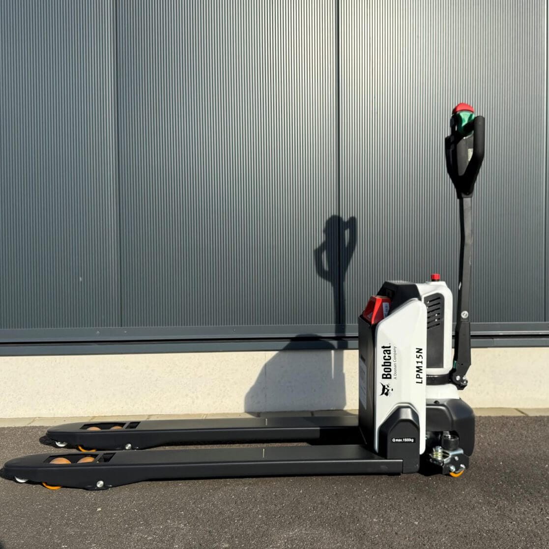 Bobcat Elektrohubwagen LPM15N steht auf Betonboden vor einer Wellblechwand, Gabelstapler Industrie Lagerlogistik sichtbar.