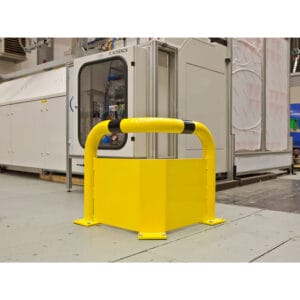 Gelber BLACK BULL Eck-Rammschutz-Bügel als Anfahrschutz vor großer weißer Industriemaschine auf Fabrikboden installiert.