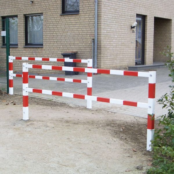 PARAT Gatterschranke, rot-weiße Metallbarriere auf Schotterweg vor Gebäude, dient als Durchfahrtssperre und Fußgängerführung.