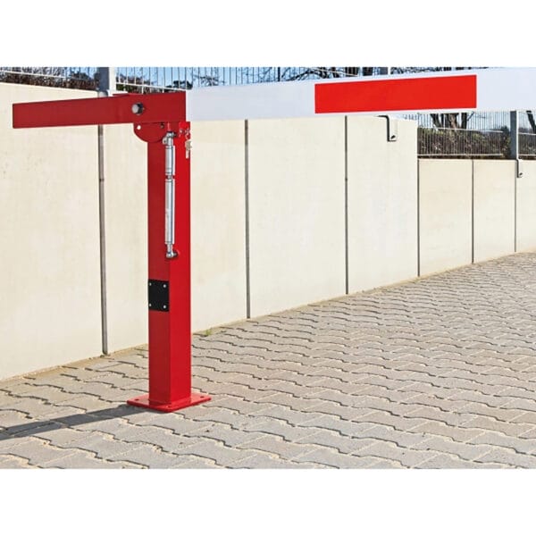 Rote und weiße COMPACT Handschranke aus Metall, montiert auf gepflastertem Boden neben beiger Betonwand im Außenbereich.