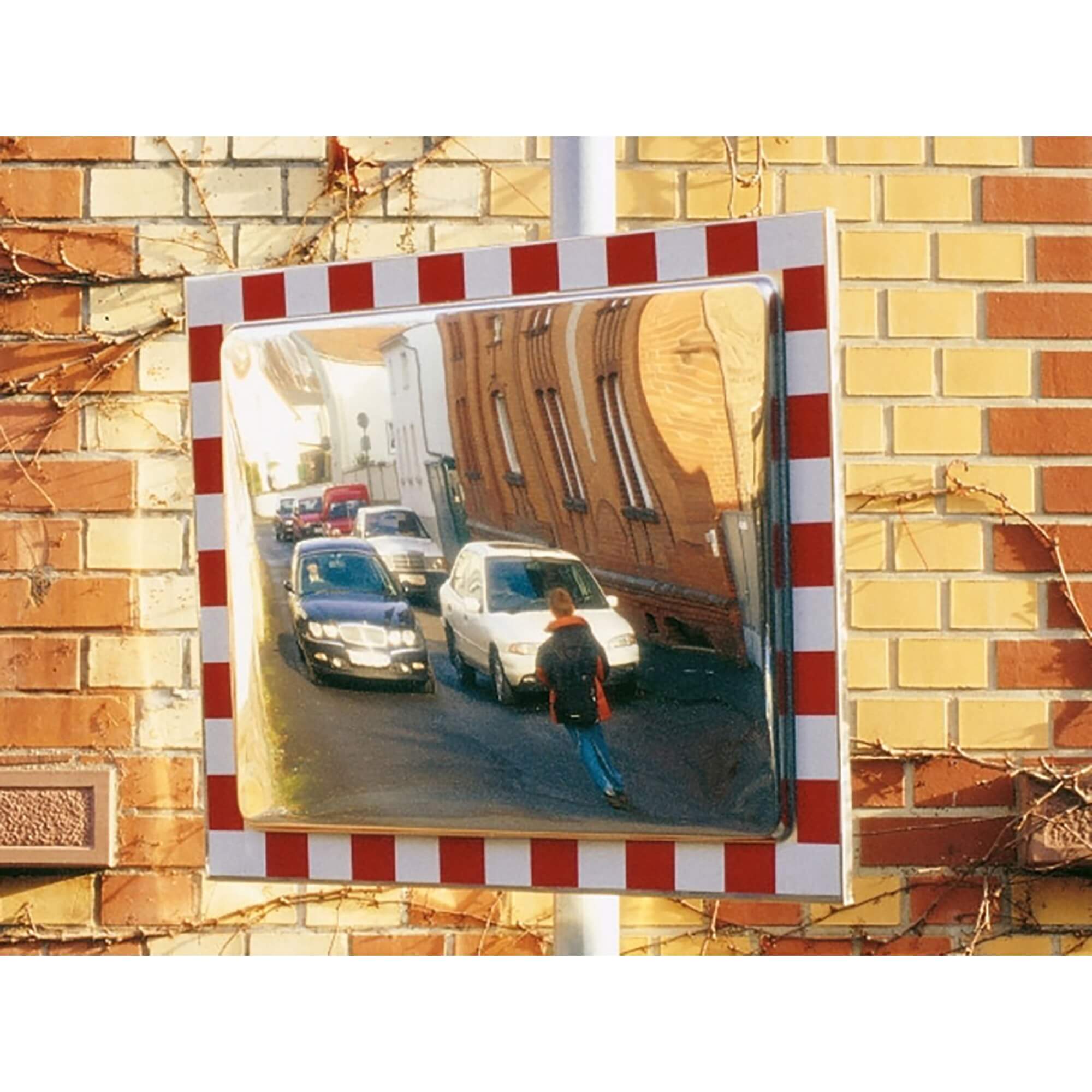 DURABEL PRO Verkehrsspiegel an Ziegelwand zeigt Straßenszene mit geparkten Autos und einer gehenden Person im Spiegelbild.