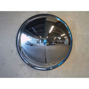 Verkehrsspiegel aus Kunststoff an Betonwand zeigt Parkhaus mit geparkten Autos und Deckenbeleuchtung im Spiegelbild.