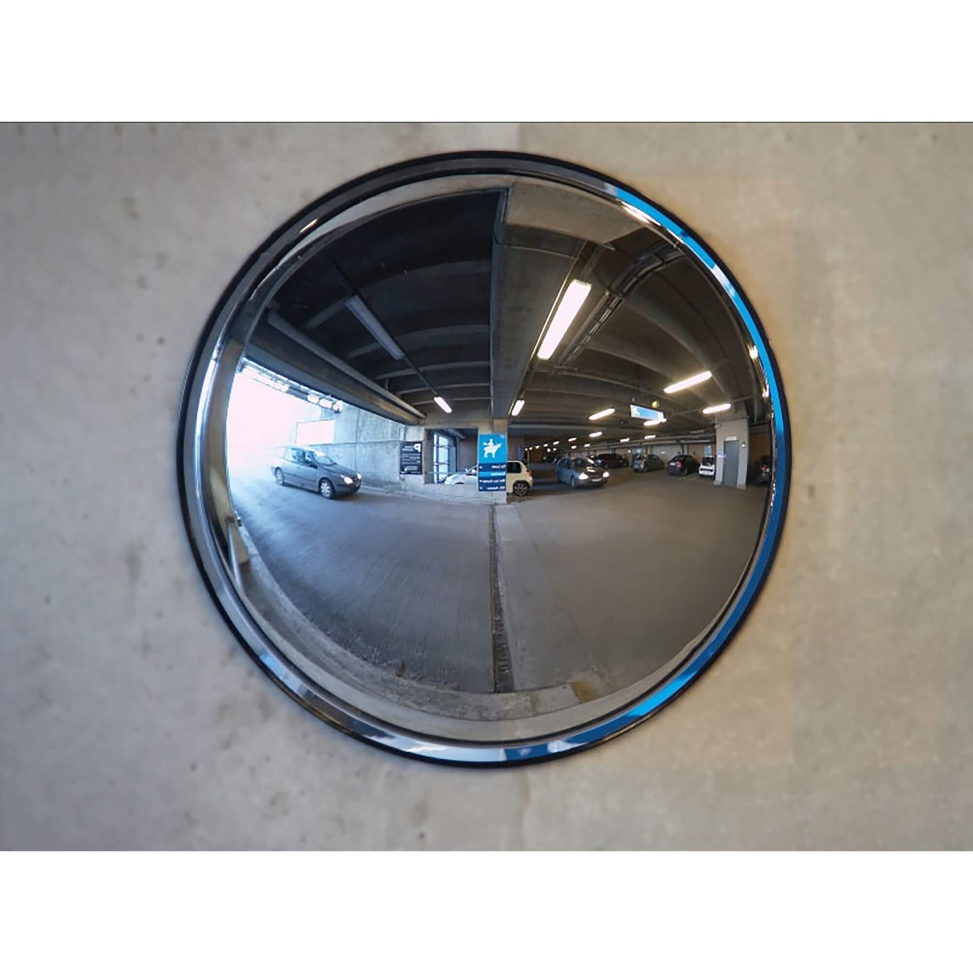 Verkehrsspiegel aus Kunststoff an Betonwand zeigt Parkhaus mit geparkten Autos und Deckenbeleuchtung im Spiegelbild.