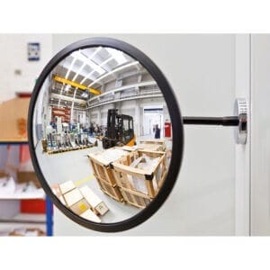 Beobachtungsspiegel mit Magnethalterung an Wand zeigt Spiegelbild von Lagerhalle, Gabelstapler, Holzkisten, Industrieregalen.