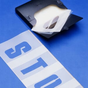 Schwarzer Ordner mit transparenten Schablonen, blaue Buchstaben S und T, Schablonensatz 30 cm, auf blauem Untergrund.