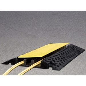 MORION Kabelbrücke mit gelbem Deckel schützt Kabel auf Asphalt, verhindert Stolpergefahr und sorgt für sichere Bodenführung.
