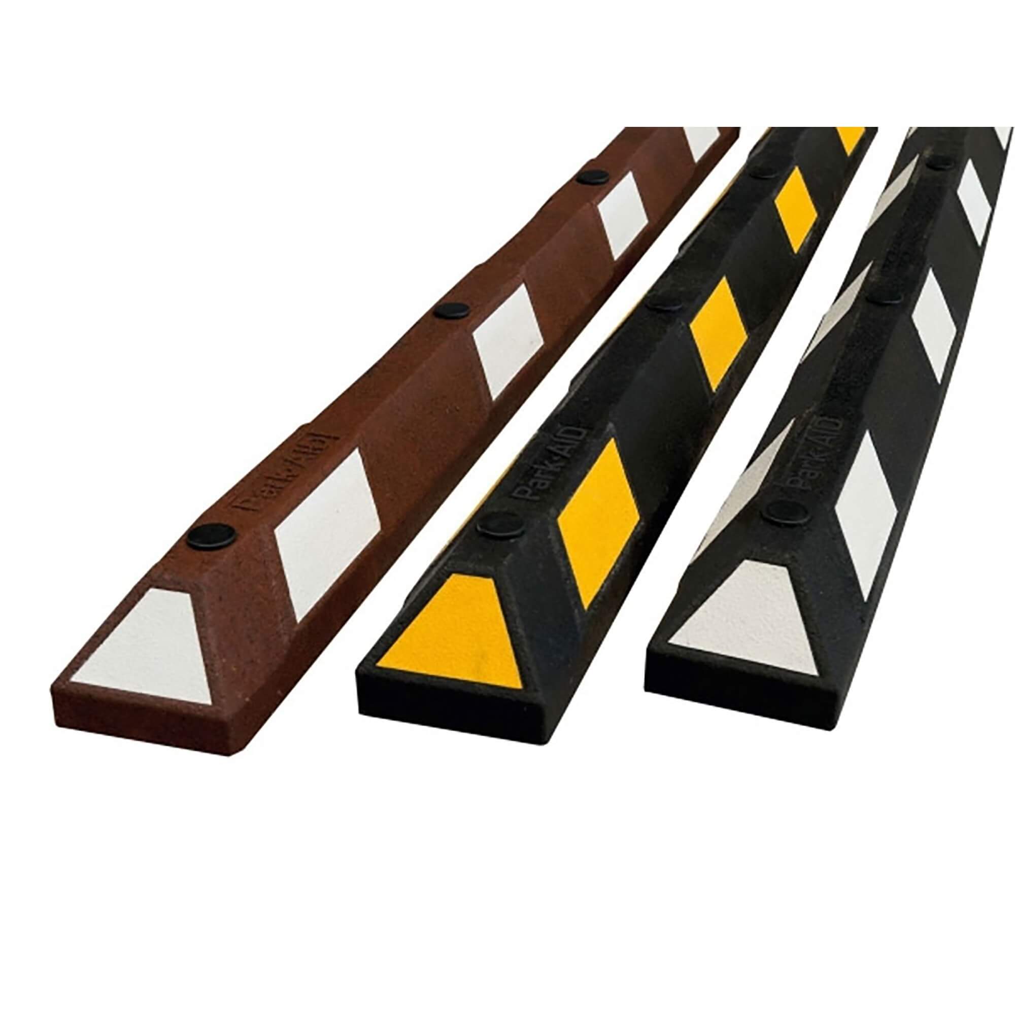 Drei Radstopp-Parkhilfen in Braun, Gelb-Schwarz und Schwarz-Weiß liegen parallel auf weißem Hintergrund.