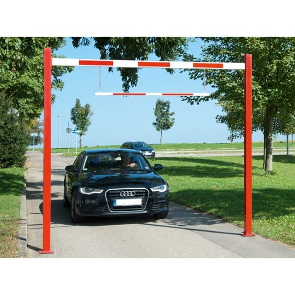 Schwarzes Auto hält unter rot-weißer COMPACT Durchfahrtbegrenzung auf Asphaltstraße; weiteres Auto im Hintergrund sichtbar.