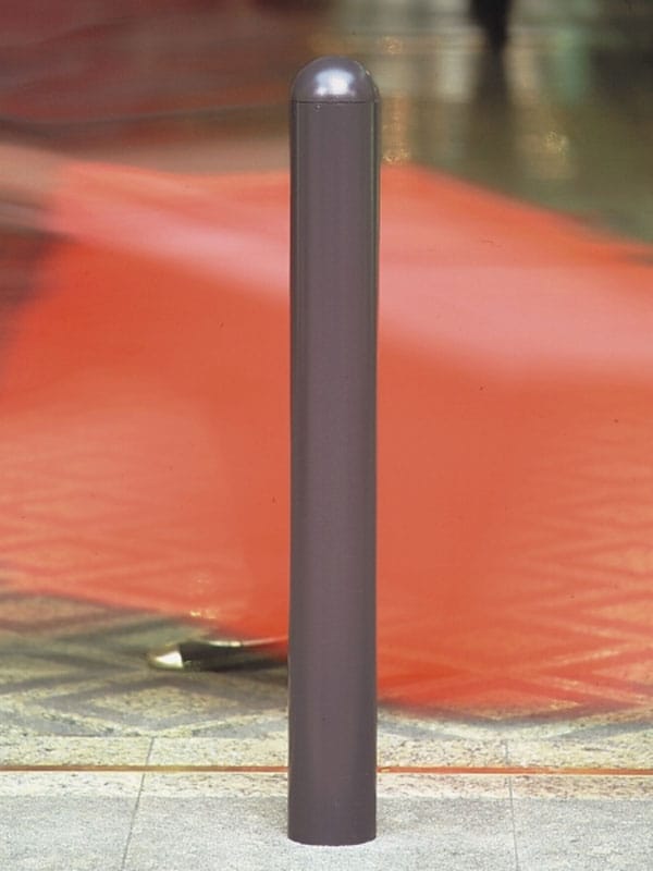 Grauer City-Poller WIEN 76 aus Metall steht auf gefliestem Boden, im Hintergrund fährt ein rotes, unscharfes Objekt vorbei.