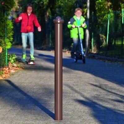 Metallpoller City-Poller POTSDAM auf gepflastertem Weg, zwei Kinder im Hintergrund, eines mit Roller, eines zu Fuß.