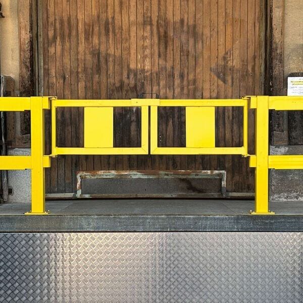 U-förmiger Stahlriegel vor geschlossener hölzerner Verladerampentür, unten silberne Riffelblech-Platte.