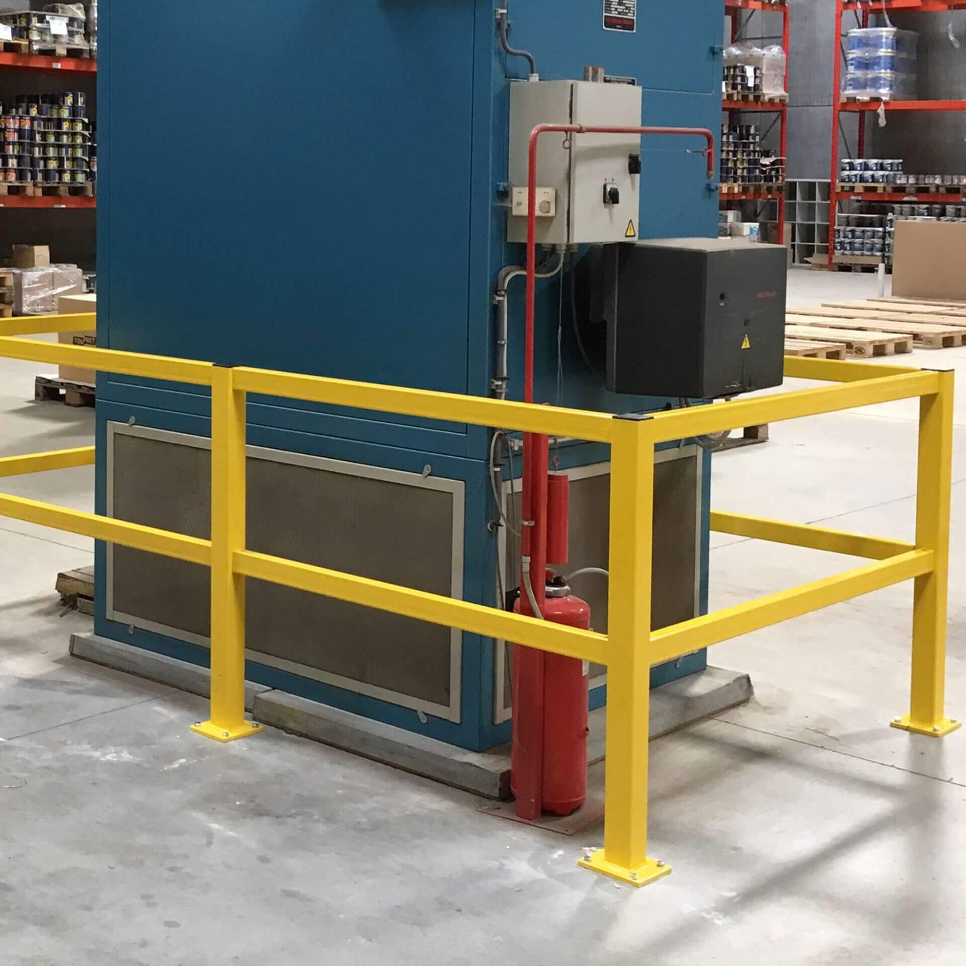 BLACK BULL Rammschutzgeländer S-line umgibt Industriemaschine in Lagerhalle, daneben roter Feuerlöscher montiert.