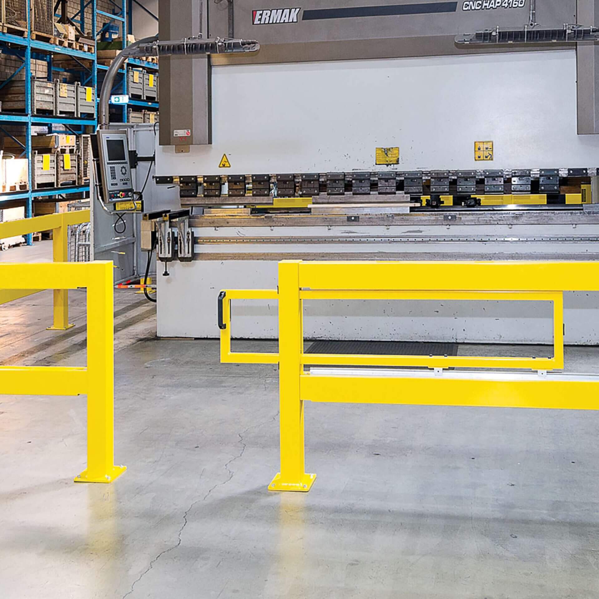 BLACK BULL Schiebetür hinter gelben Schutzgeländern in Lagerhalle mit Betonboden und Regalen, Zugang zu Industriemaschinen.
