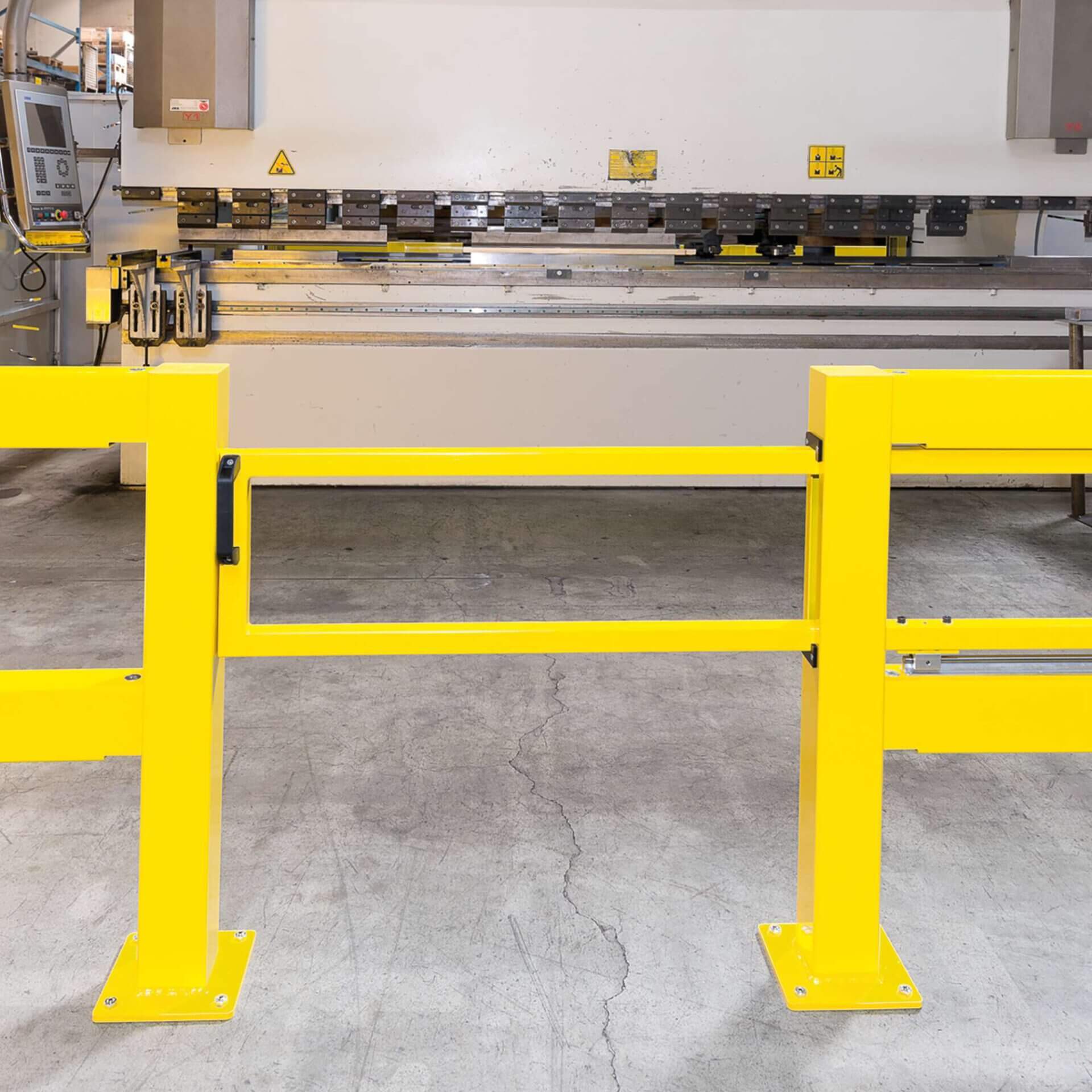 Gelbe BLACK BULL Schiebetür-Sicherheitsbarriere vor Industriemaschine auf Betonboden, mit Bedienfeld und Warnschildern.