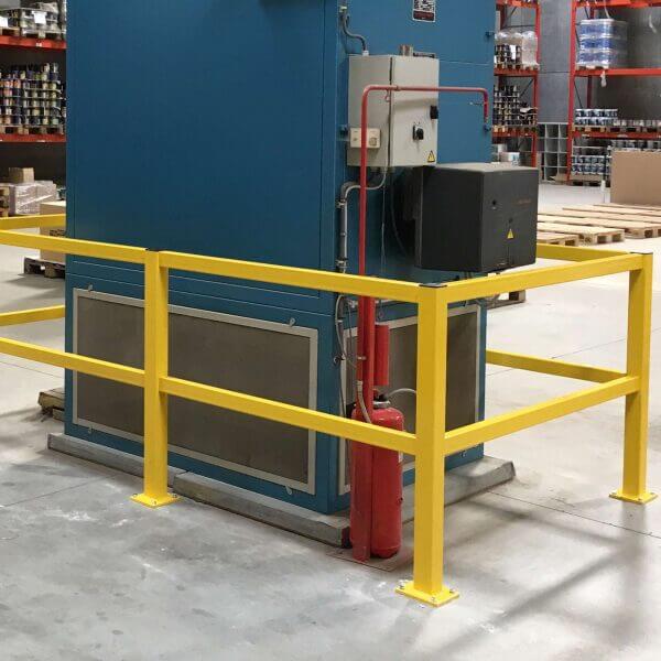 Gelbes BLACK BULL Rammschutzgeländer S-line umgibt Industrieanlage in Lagerhalle, Steuerpulte und roter Feuerlöscher sichtbar.