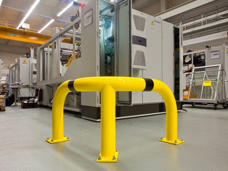 Gelb-schwarzer BLACK BULL Eck-Rammschutzbügel XL als Anfahrschutz vor Maschinen auf Hallenboden montiert.