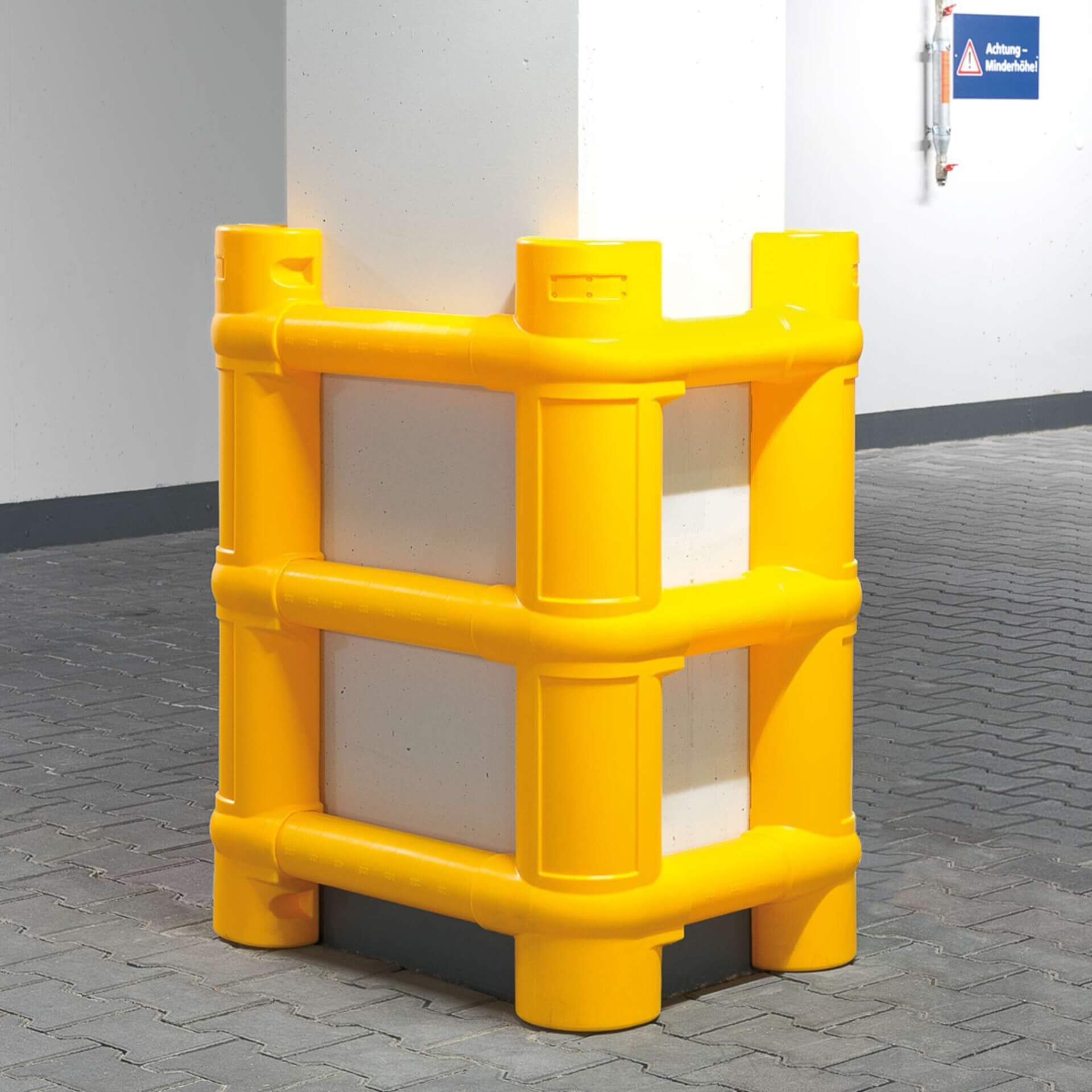 Gelber MORION Säulenschutz aus Kunststoff umgibt weiße, quadratische Pfeiler auf gepflastertem Hallenboden zum Aufprallschutz.