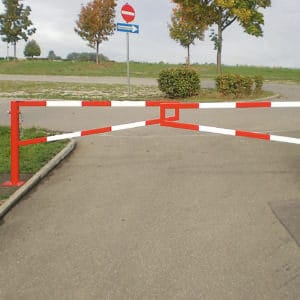 MORION Gatterschranke sperrt gepflasterten Weg, daneben Einfahrt verboten Schild und Richtungspfeil, Bäume säumen den Bereich.