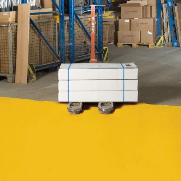 Palettenhubwagen mit drei weißen Kartons und blauen Gurten auf PROline-paint Hallenboden, Regale und Kartons im Lager.