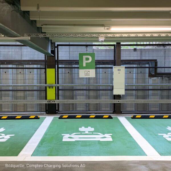 Zwei grüne Elektroauto-Parkplätze mit Ladesäulen und Radstopp Park-AID, klar markiert im überdachten Parkhaus.