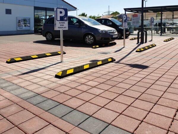 Behindertengerechte Parkplätze, geparkte Autos und Radstopp Park-AID Parkstopper auf einem Parkplatz vor einem Gebäude.