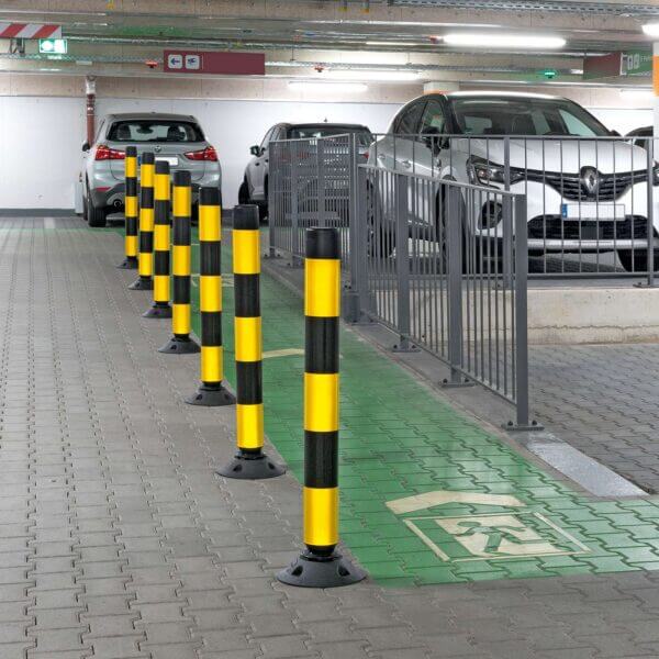 Sieben gelb-schwarze FlexPin-Poller trennen einen grün markierten Behindertenparkplatz von normalen Parkplätzen in Tiefgarage.