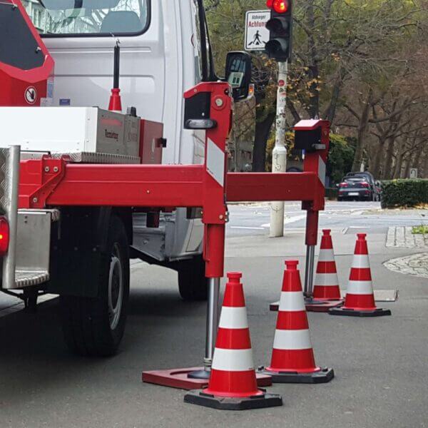 Lkw mit ausgefahrenen Stützfüßen steht auf Straße; MORION ReflexKegel EU Leitkegel nahe roter Ampel platziert.