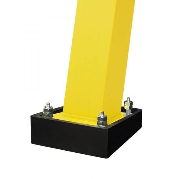 Gelber Metallpfosten fest mit vier Schrauben auf schwarzer rechteckiger Bodenplatte montiert, Nahaufnahme vor neutralem Hintergrund.