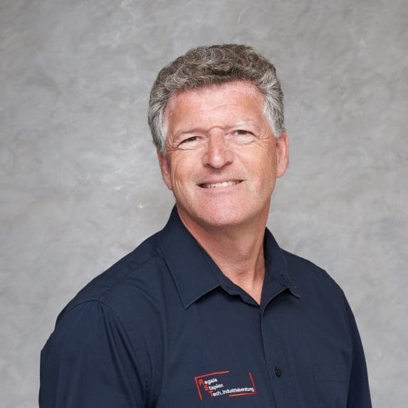 Mittelalterlicher Mann mit kurzem grauem Haar, dunkles Hemd, Namensschild, vor hellgrauem Hintergrund, Technische Beratung.