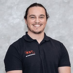 Mann mit kurzem grauem Haar lächelt, trägt dunkles Hemd vor hellem Hintergrund; Porträt für Technische Industrieberatung.