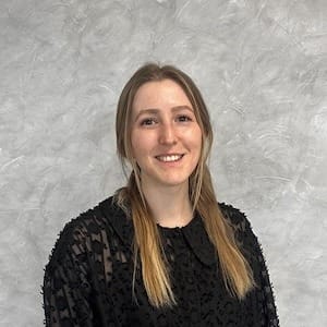 Mann mit kurzem grauem Haar lächelt, trägt dunkles Hemd vor hellem Hintergrund; Porträt für Technische Industrieberatung.